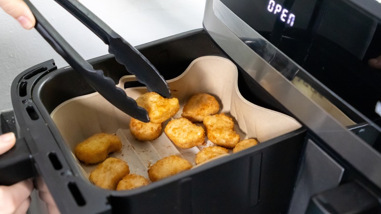 Someone cooking chicken nuggets in an air fryer