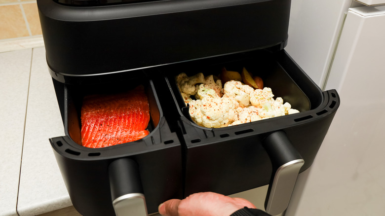 Air fryer with two baskets full of different foods