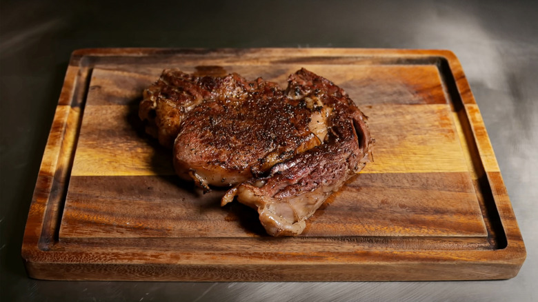 Grilled steak resting on wooden cutting board