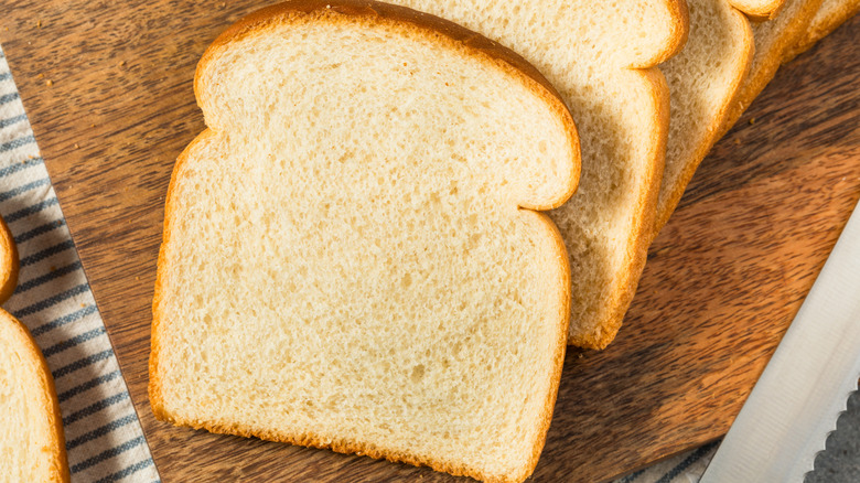 Slices of white sandwich bread on wooden cutting board