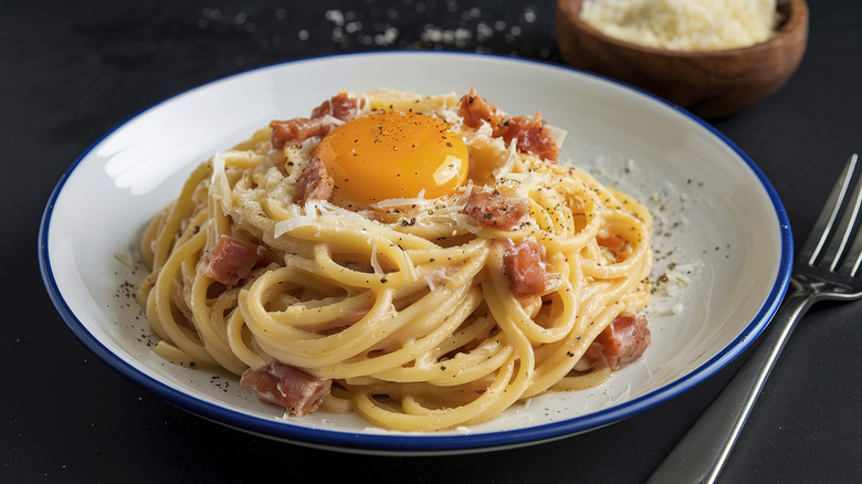 Bowl of spaghetti carbonara with raw egg yolk on top