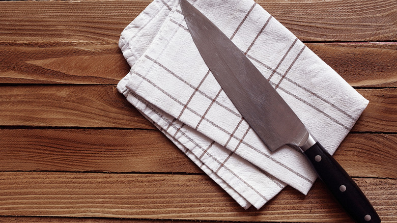 A top-down view of a chef's knife lying on a white towel