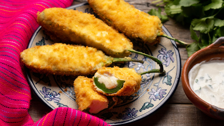fried jalapeno poppers on a plate next to creamy dipping suce