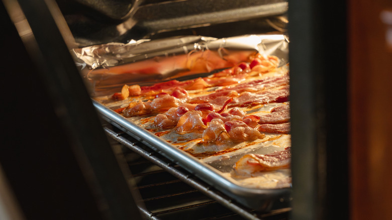 Strips of bacon cooking on a tray in the oven