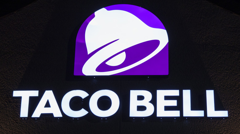 A neon purple and white Taco Bell sign in the dark.