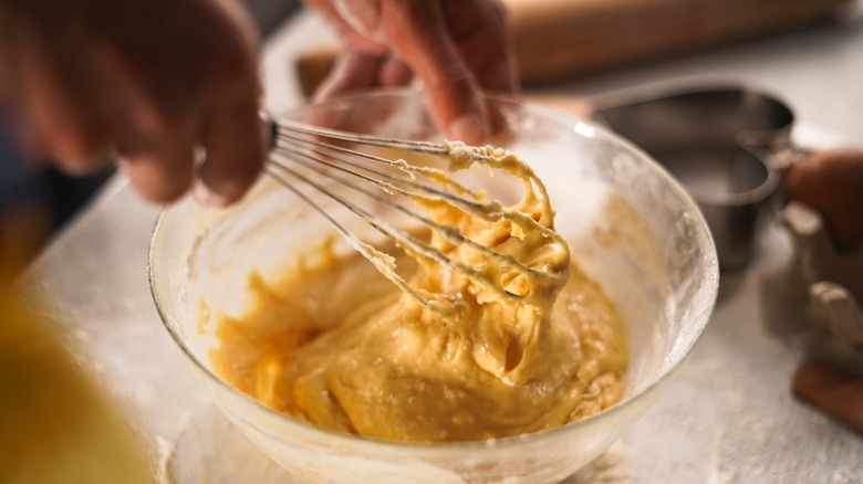 A home baker whisks batter in a glass bowl