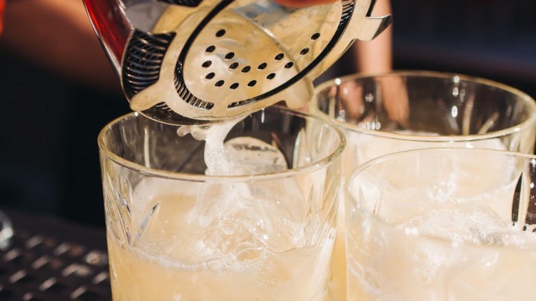 bartender pouring margaritas into rocks glasses
