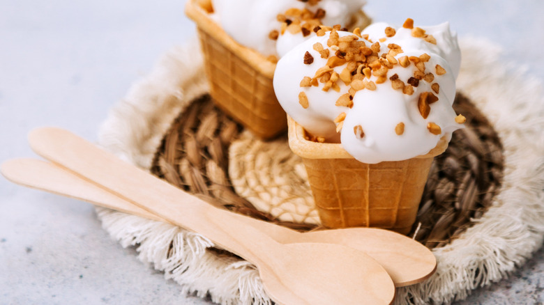 waffle cone bowl with whipped cream, nuts, wood spoons