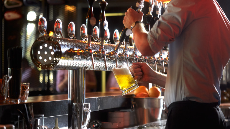 Bartender pouring beer from a tap at a brewery.