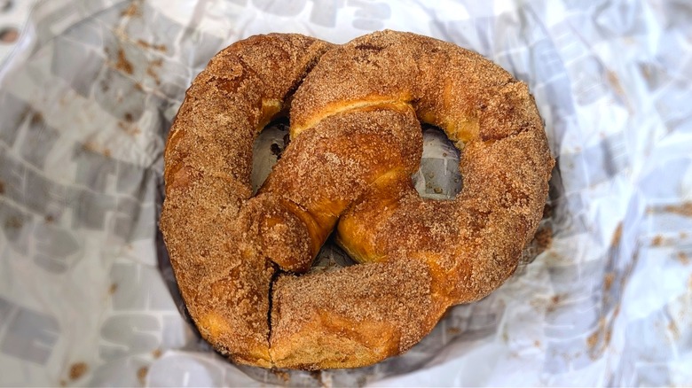 Close-up of a cinnamon sugar soft pretzel on messy white paper