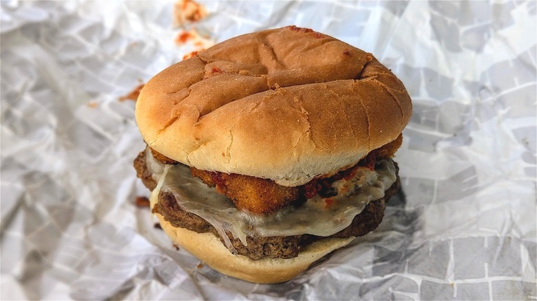Close-up of a burger with mozzarella sticks on white paper