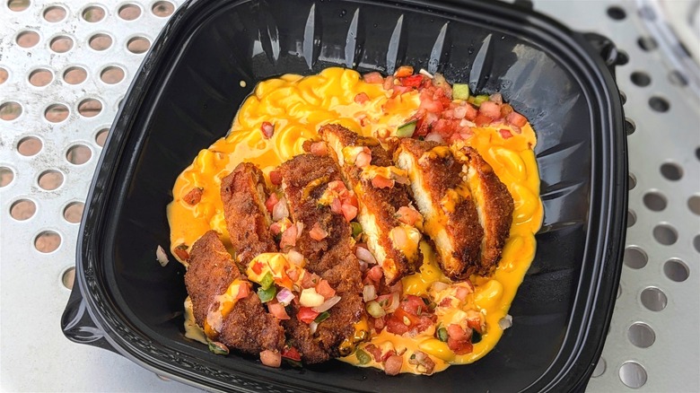 Saucy mac and cheese with pico and breaded chicken in a black plastic container