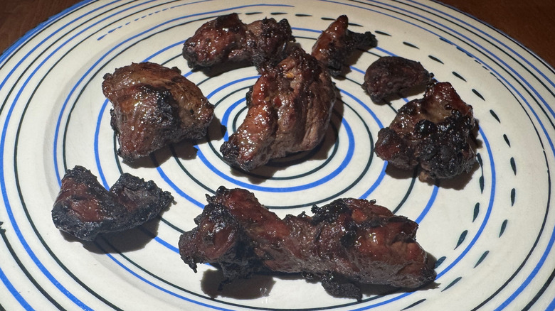 Nuggets of grilled steak on a blue and white serving platter.