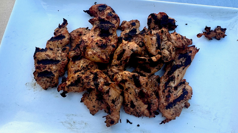 Grilled chicken tenders with pronounced grill marks on a white serving platter.