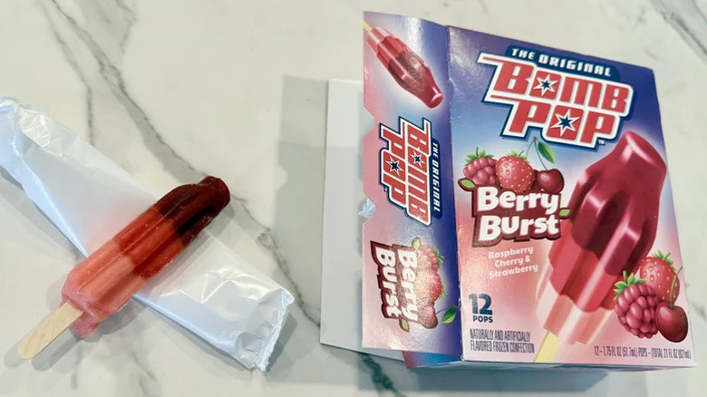 A box of Berry Burst Bomb Pops next to an opened one on a table.