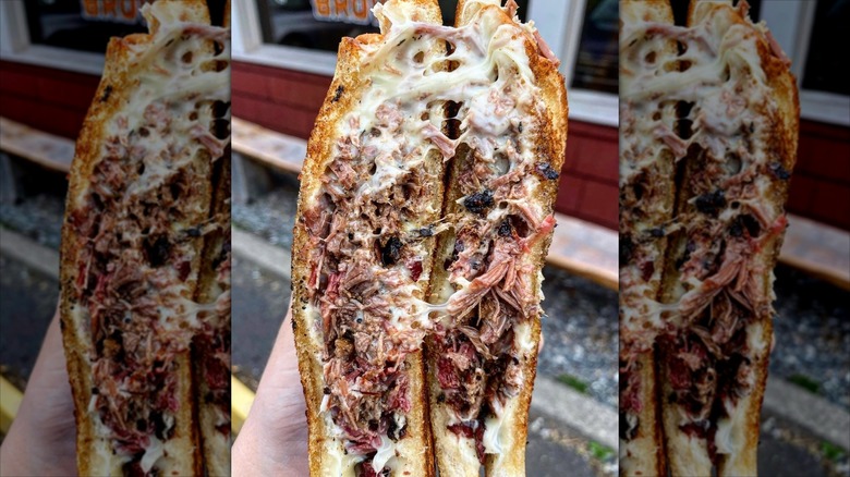 Hand holding up Brisket Grilled Cheese sandwich from Hoodoo Brown BBQ