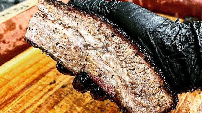 Gloved had holding brisket slice from Sunset Texas Barbecue