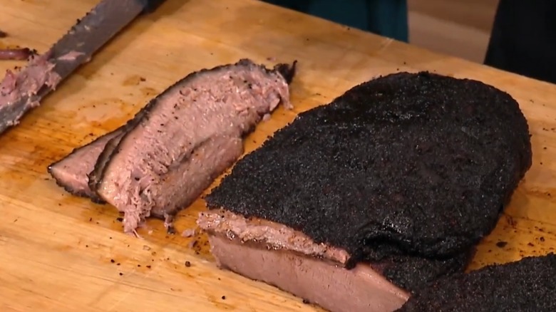 Brisket sliced on a wooden cutting board with cutting knife in background from Smoque BBQ