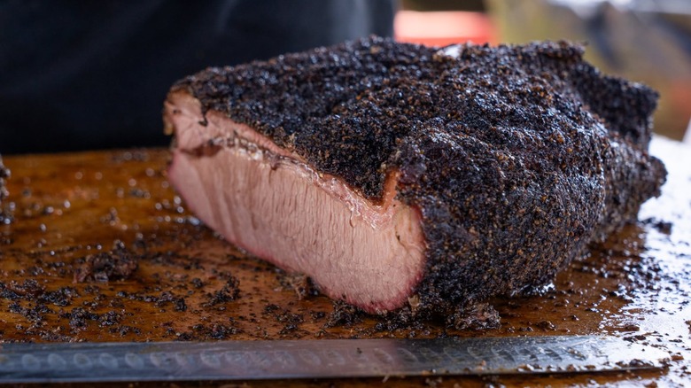 Brisket on cutting board with cutting knife in front from Whatcha Smokin? BBQ + Brew