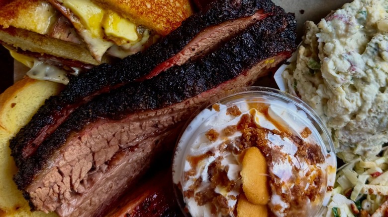 Sliced brisket with various sides, like potato salad and banana pudding, from Mad Jack's Mountaintop Barbecue