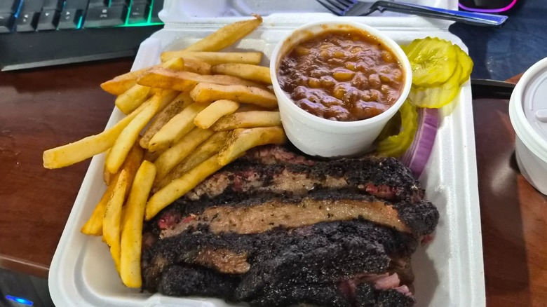 Sliced brisket with sides of French fries, baked beans, and pickles and onions from Lukes BBQ LLC