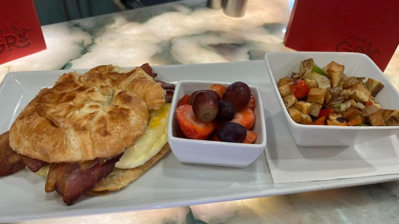 The Grumpy Rabbit bacon egg and cheese croissant with potatoes O'Brien and fruit