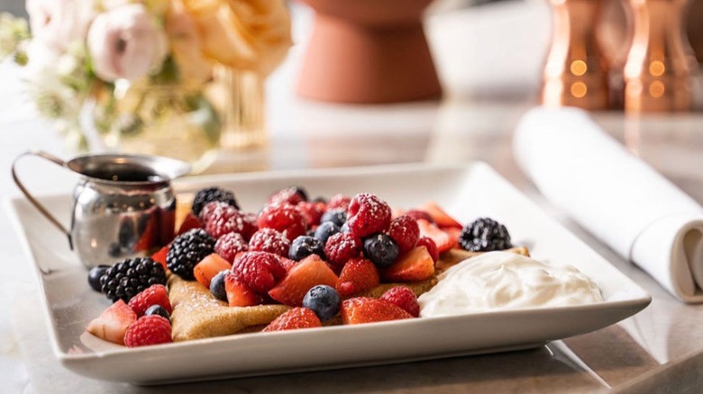 Onefold brunch featuring fresh fruit topped crepes with side of syrup and cream