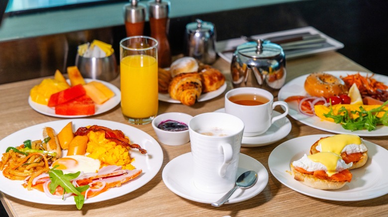 Restaurant brunch spread on table with plates of eggs, pastries and coffees and juices