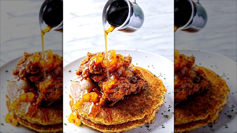 Syrup poured over Easy Like Sunday's fried chicken and cornmeal pancakes with Peach habanero jam and Maple butter