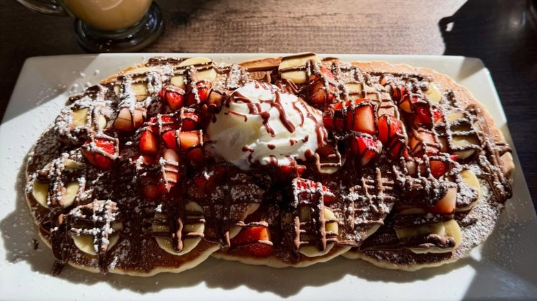 AmeriBrunch Cafe pancakes topeed with drizzled chocolate, bananas, and strawberry
