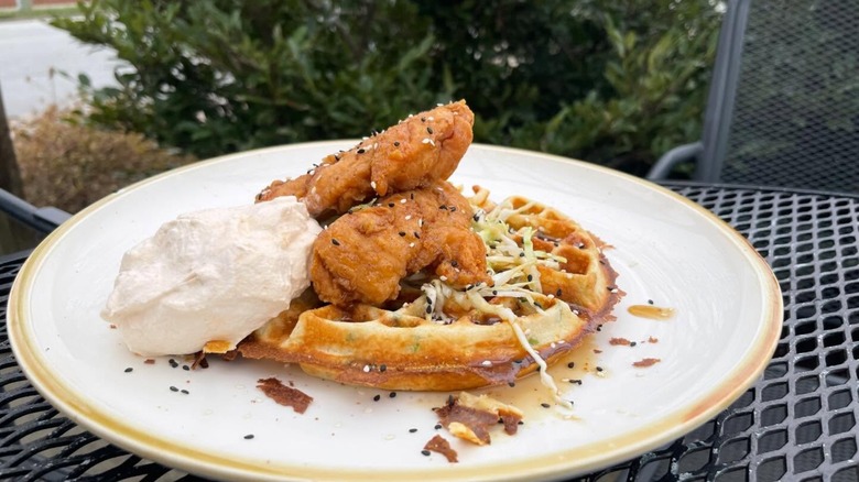 The Sage Mule chicken and waffle is made with a scallion-sourdough waffle, orange-soy glaze, toasted sesame cabbage, and gochuhjang whipped cream