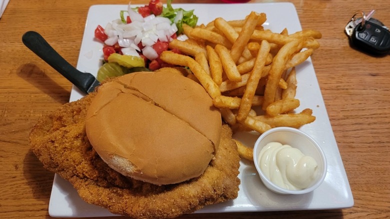 A sandwich with fries and mayo on a square plate