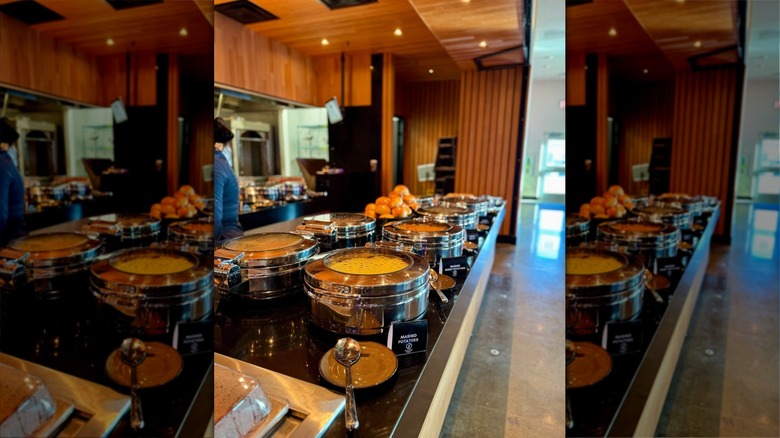 Buffet line with silver containers and serving spoons at Fyre Modern Grill