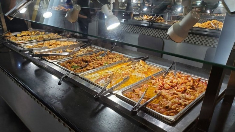 Various items in trays with serving tongs from buffet line at River Buffet & Grill