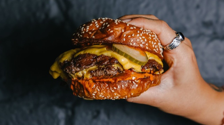 A hand holding The Legendary Burger from Nowon in NYC