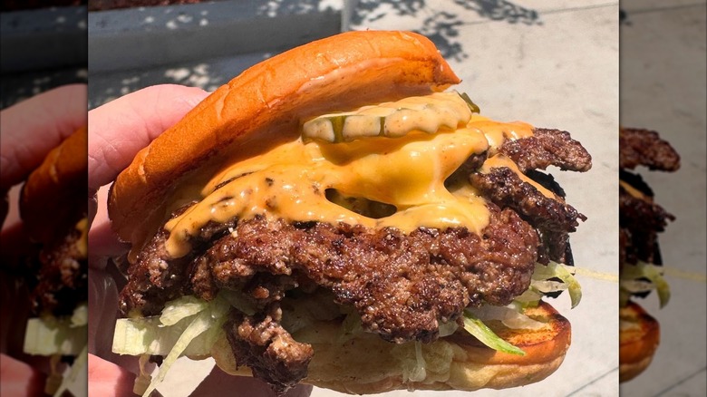 Hand holding a For the Win double smash cheeseburger