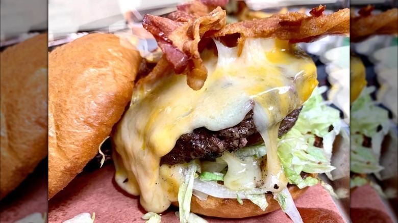 Cheese bacon burger with top bun off showing patty, cheese, bacon, and lettuce