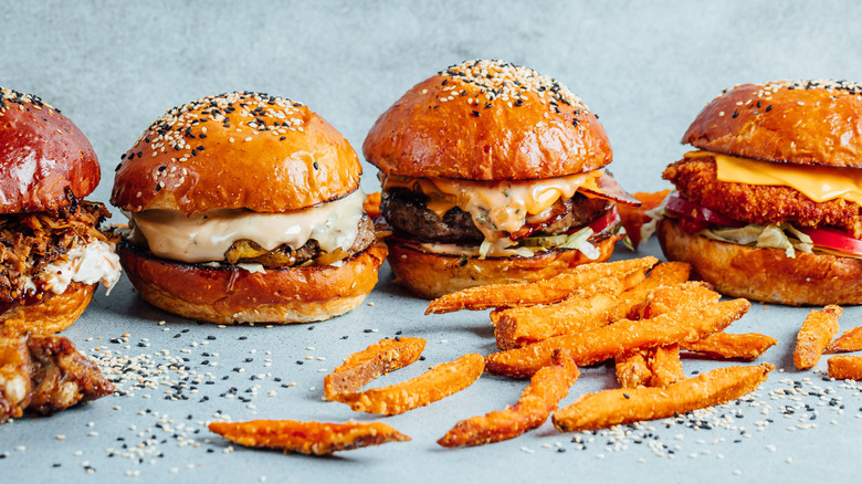 Four burgers with french fries in front of them