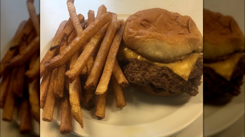Cheeseburger on a plate next to a pile of french fries