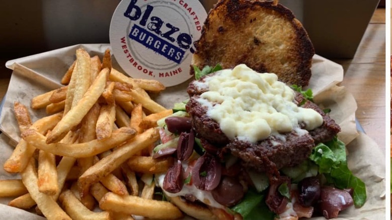 Black and Blue Burger on Plate with top bun off, next to frenche fries and a container of sauce