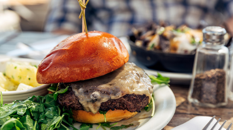 Mushroom swiss cheeseburger on a plate with greens
