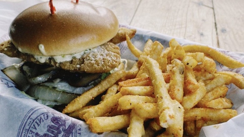 Moo Oink and Quack burger on paper in a basket with a side of fries