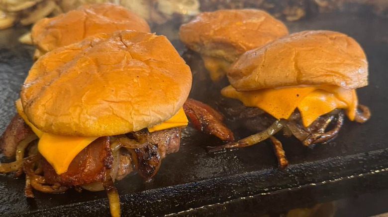 Four Onion Burgers sitting on a griddle
