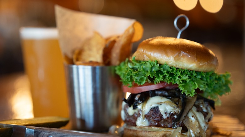 Dambach-ery Burgers on a wooden table with fries in a metal cup and a glass of beer