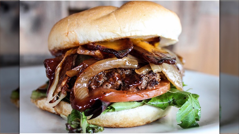 Close-up photo of Lucky 13 burger with onions, bacon, lettuce, tomato, beef