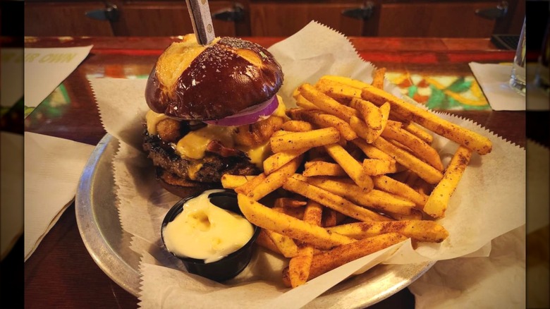 Brazen Beer Cheeseburger and fries sitting on plate next to sauce