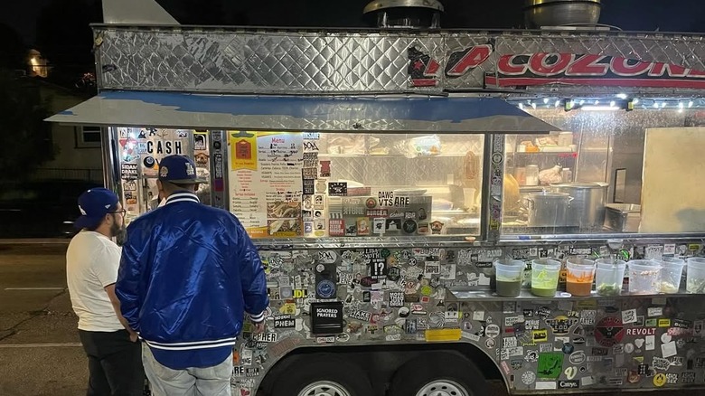 Two people outside Taco Zone truck