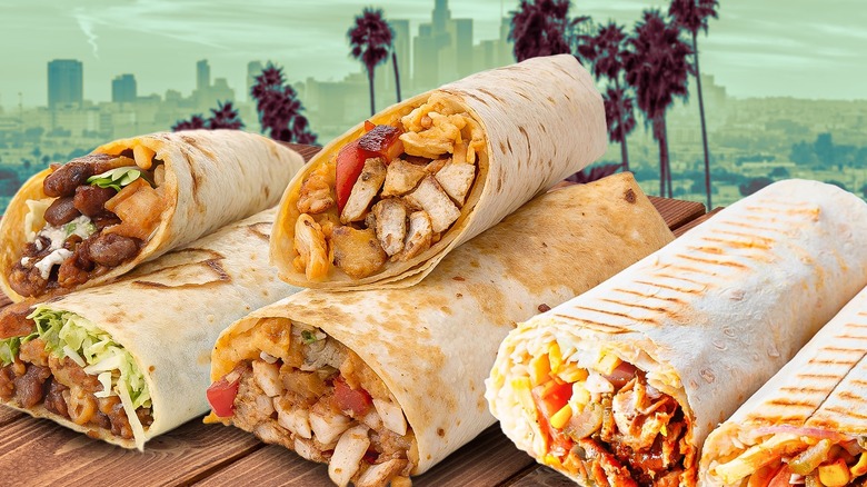 A variety of burritos against the backdrop of downtown Los Angeles