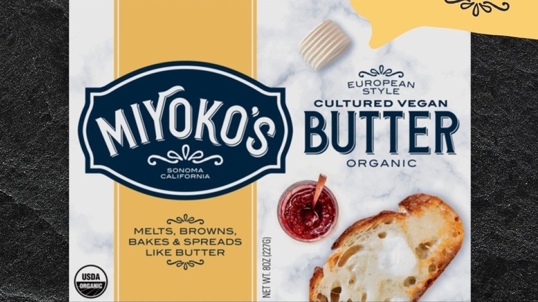 Miyokos butter block on a black granite background. A label saying vegan wax packaging blurb on the side