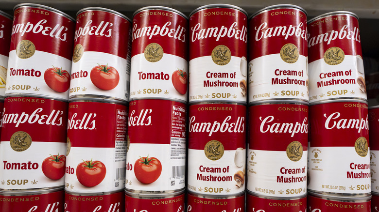 Tall stacks of Campbell's canned soups on store shelves.